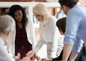 A team of people gather in a circle and discuss a project.