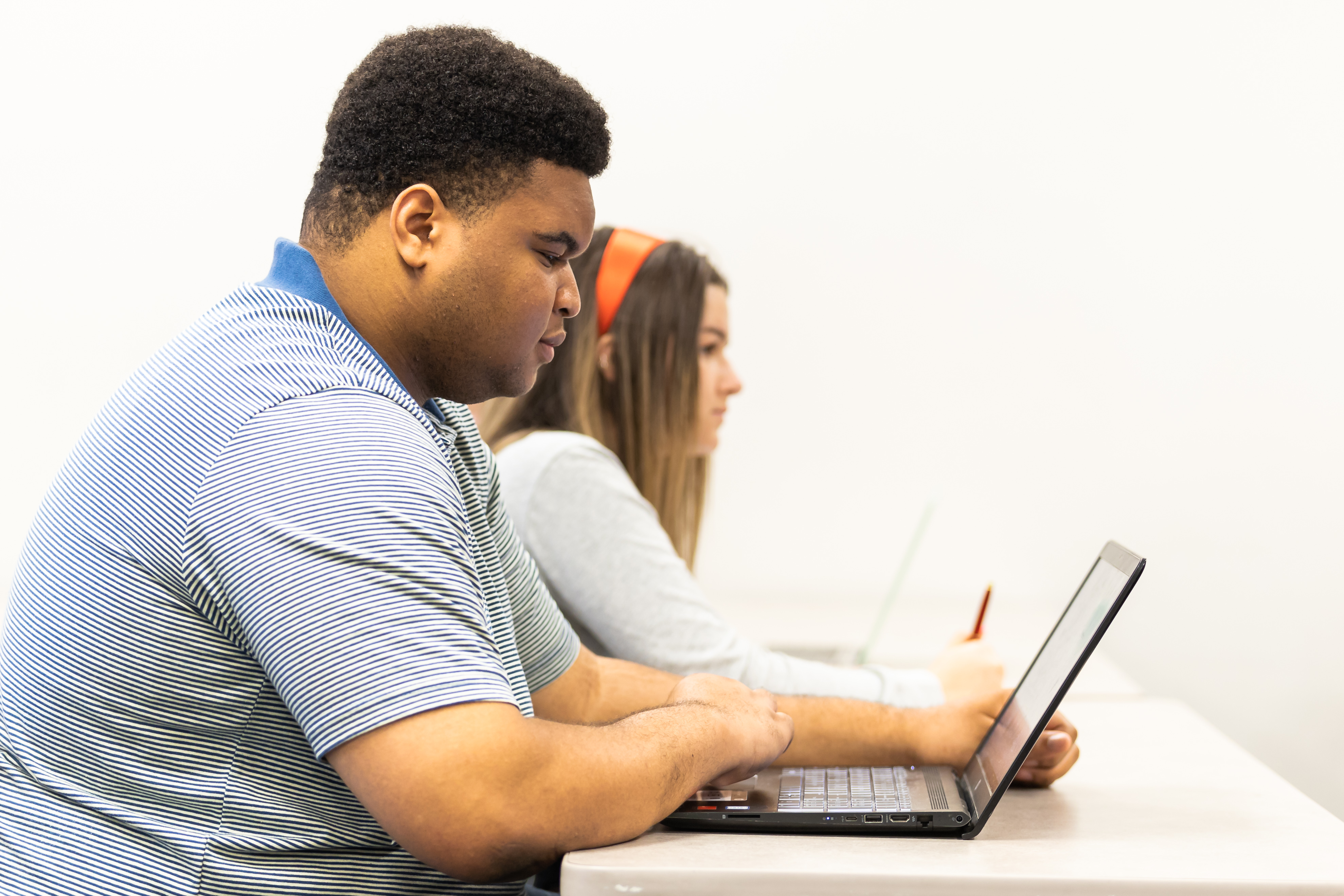 A student sits in class and looks at their laptop.