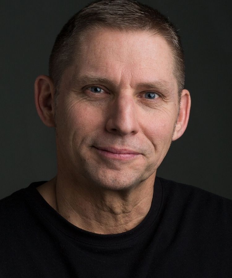 man in a dark shirt smiling at the camera
