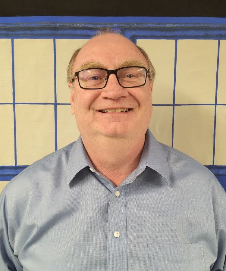 man in a blue shirt smiling at the camera