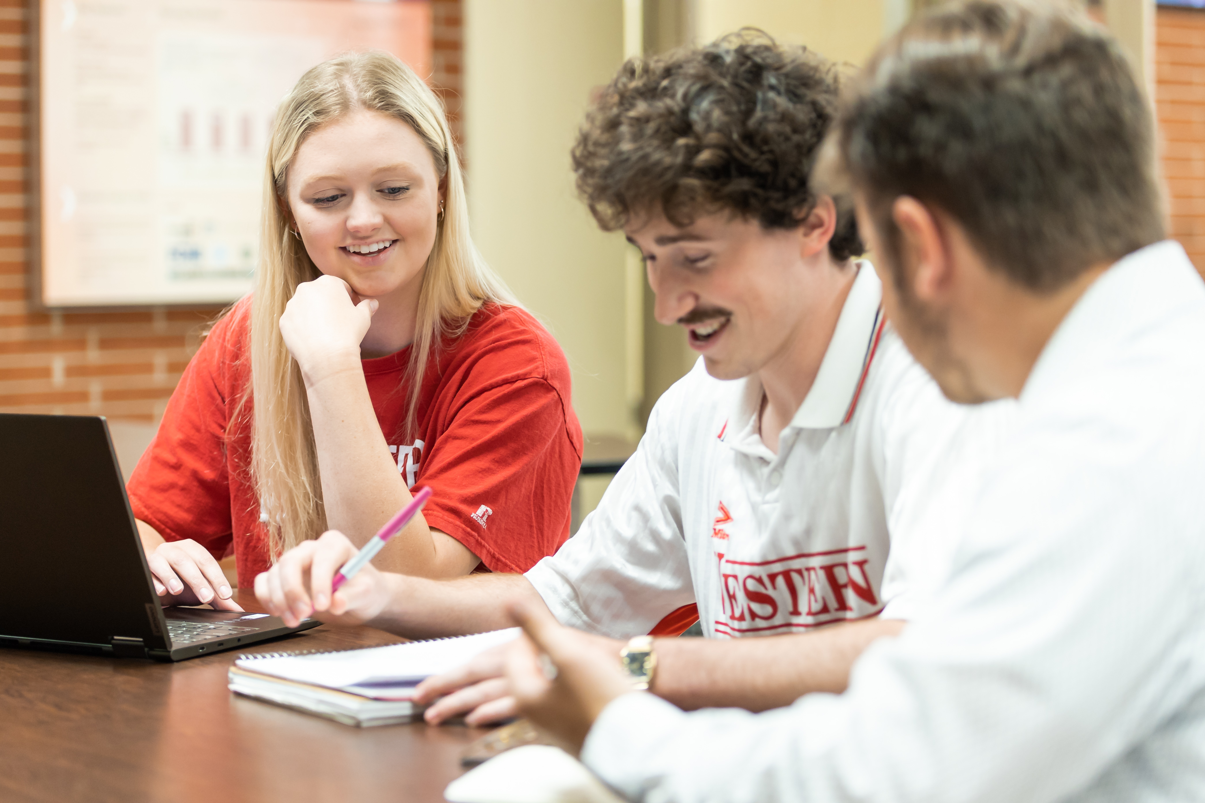 Three students sit and talk at a table in Grise Hall.
