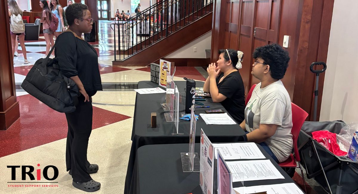 TRIO Peer Success Coaches share campus resources with a student at a table in the Downing Student Union