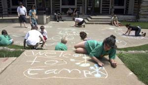 A picture of kids coloring on sidewalk with chalk